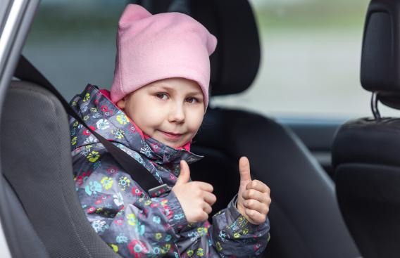 Child in a car seat giving a thumbs-up