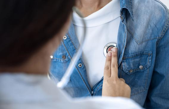 Doctor examining a women's heart with a stethoscope.