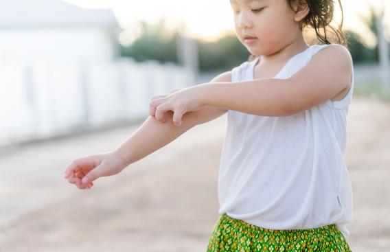 young girl itching her forearm and elbow