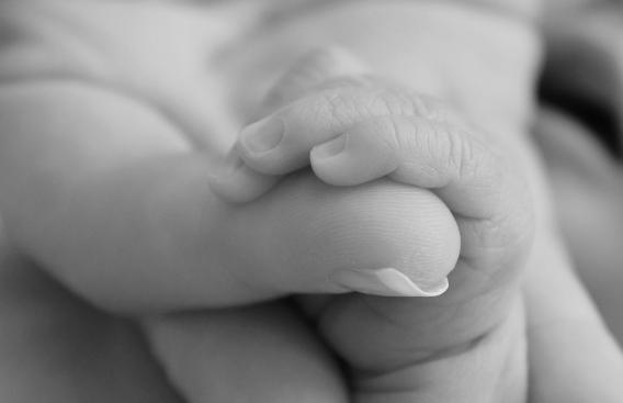 Newborn holding Mom's thumb
