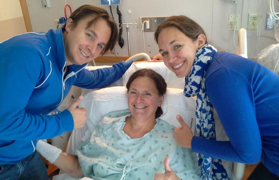 Susan Sullivan with her son and daughter at her bed side, smiling