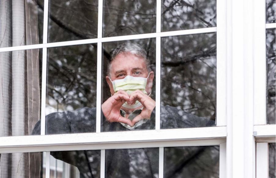 Senior behind window wearing mask.